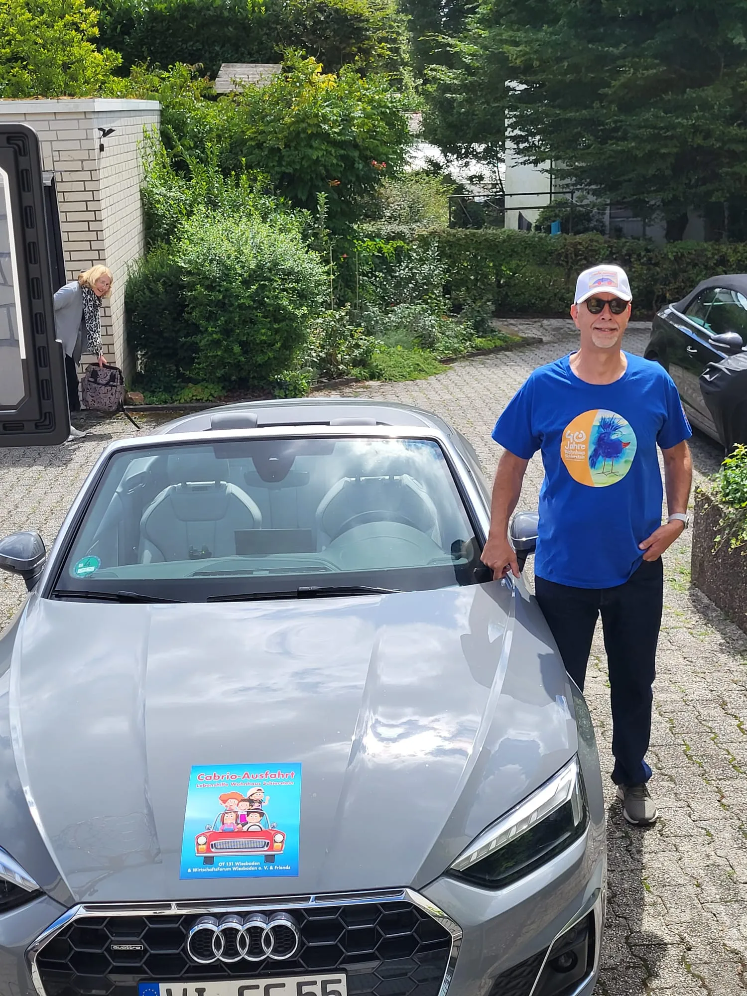 Peter Hoffmann, Initiator und Organisator der Cabrio-Ausfahrt, am Cabrio mit dem Ausfahrt-Plakat
