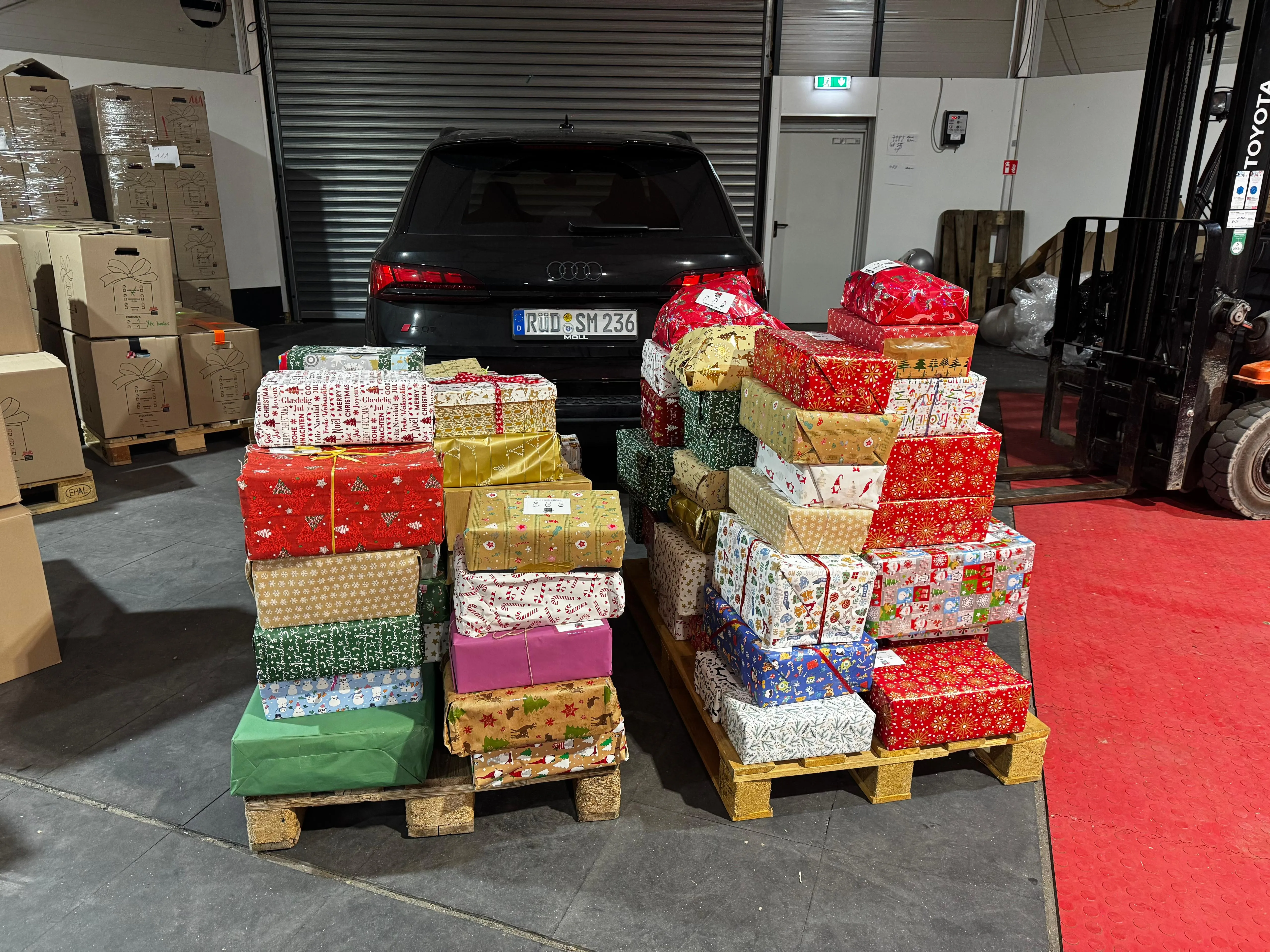 Gestapelte, weihnachtlich verpackte Päckchen auf Paletten, bereit für den Weihnachtspäckchenkonvoi